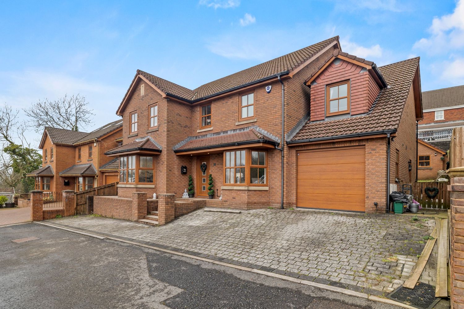 Modern red brick detached house with integrated garage and block paved driveway.