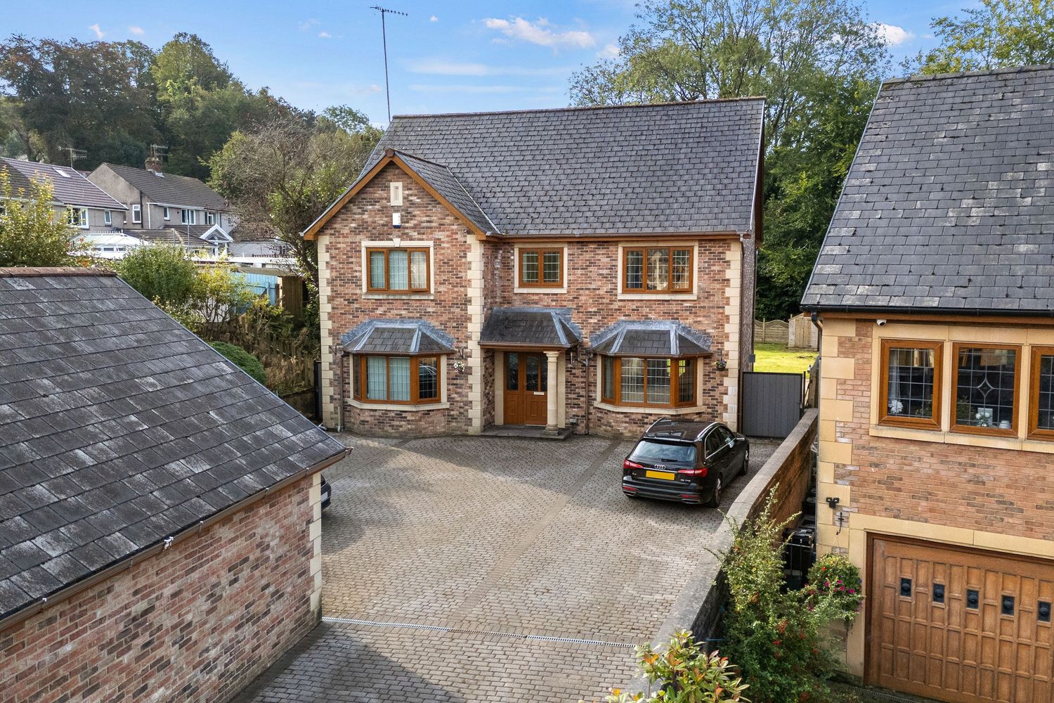 Traditional brick-built detached house with double garage and cobblestone driveway.