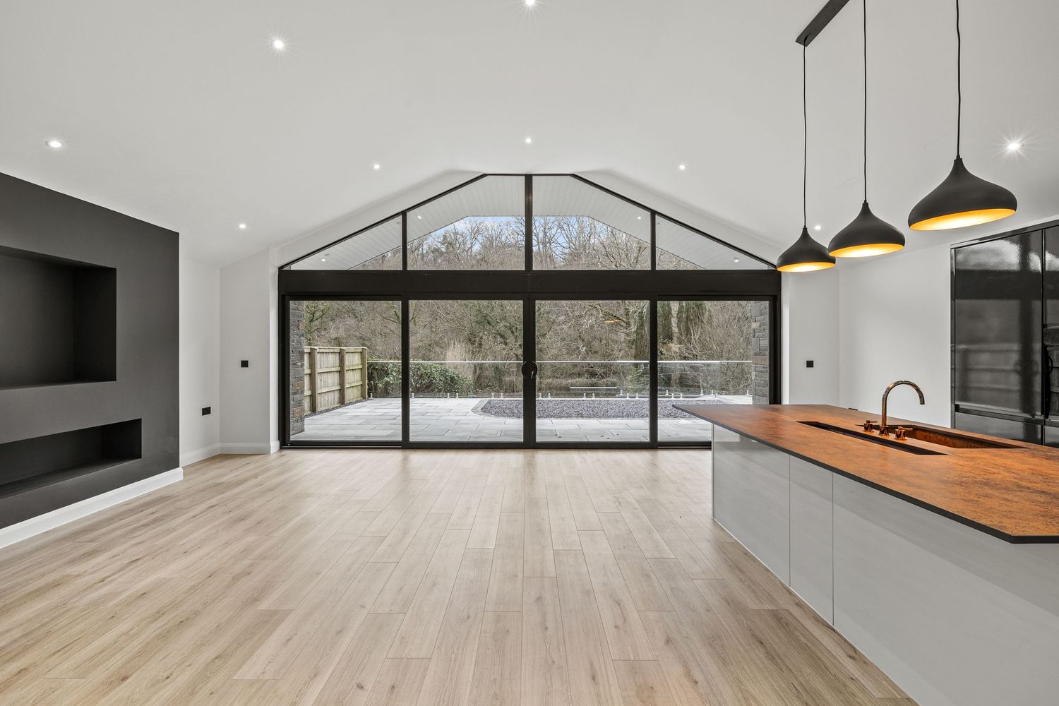 Open concept living space with vaulted ceiling, large windows, and modern kitchen island.