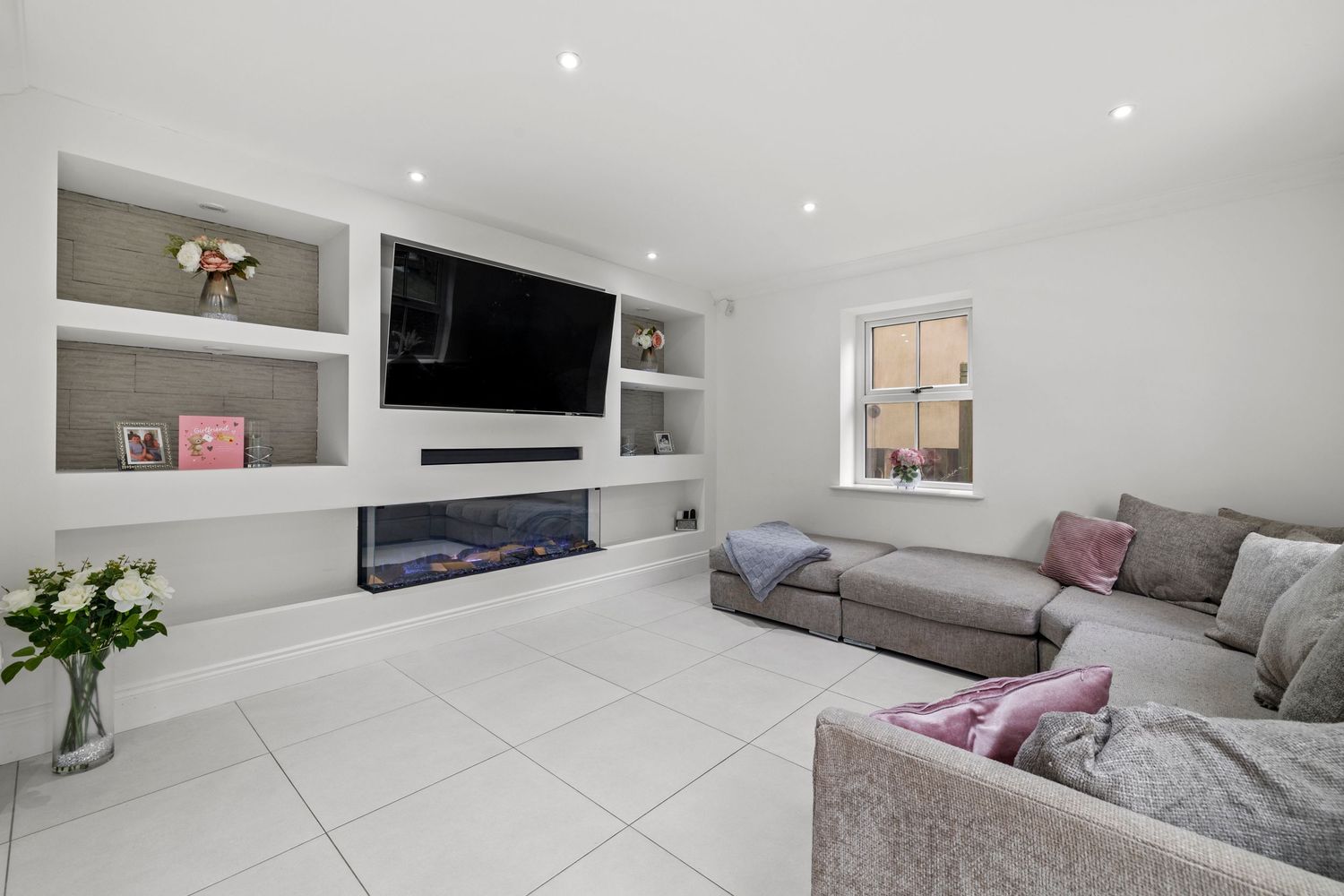 Contemporary living room with built-in entertainment unit, fireplace and grey L-shaped sofa.