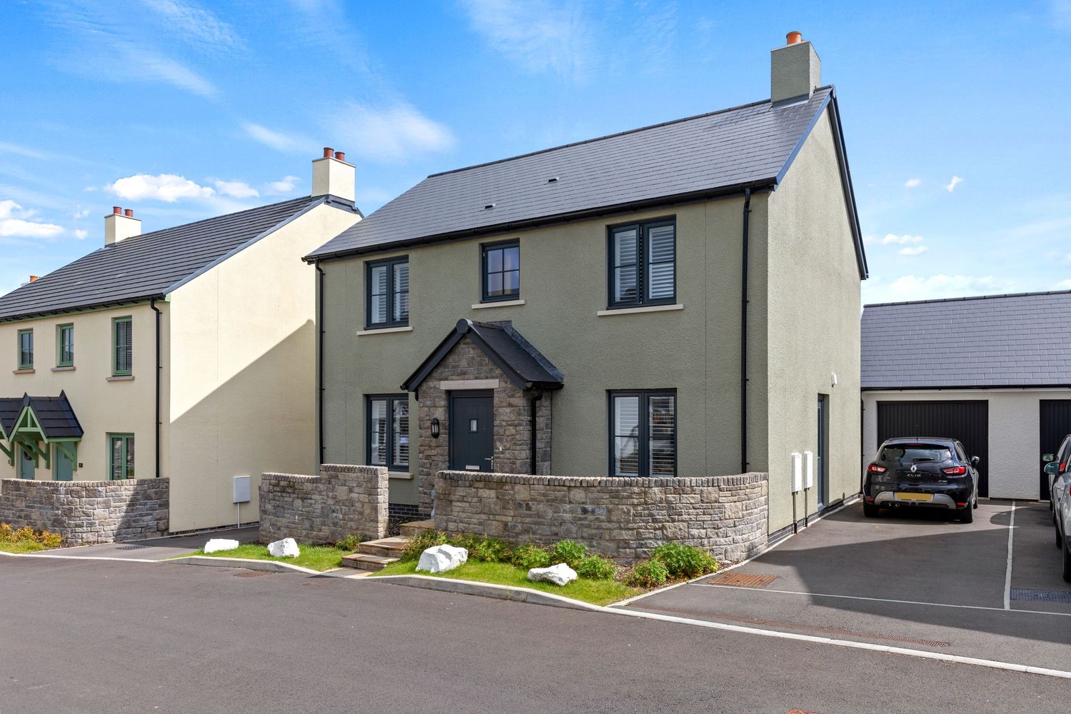 Traditional stone-detailed house with attached garage and manicured landscaping.