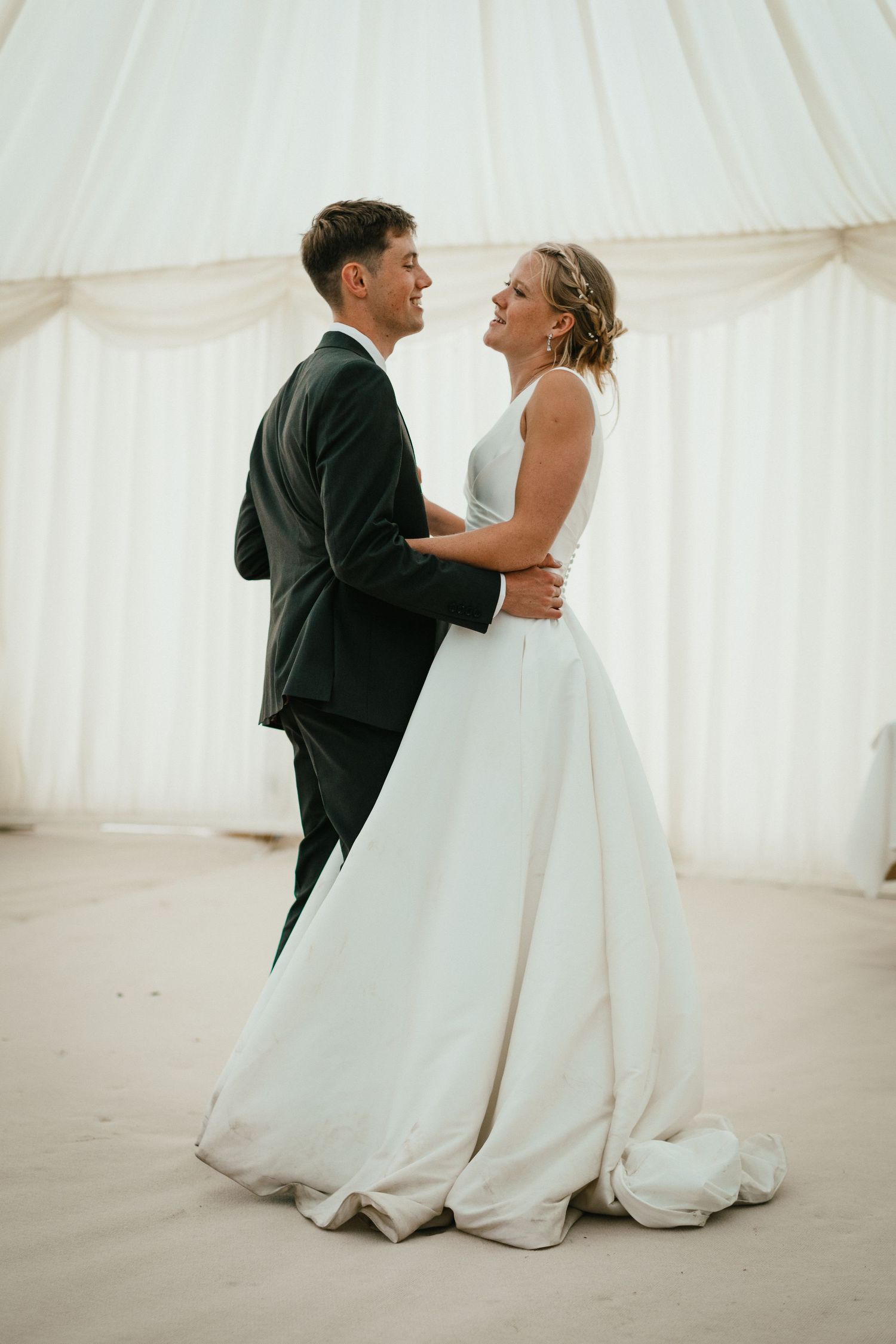 Intimate moment between couple during their first dance in white wedding tent setting.