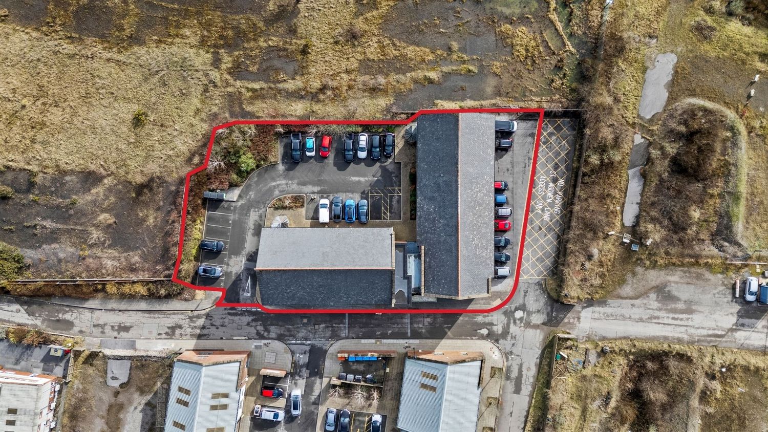 Drone shot of a commercial building with parked cars and red boundary markers.