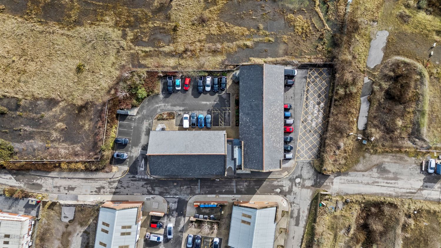 Top-down view of a commercial facility with parked vehicles and adjacent structures.