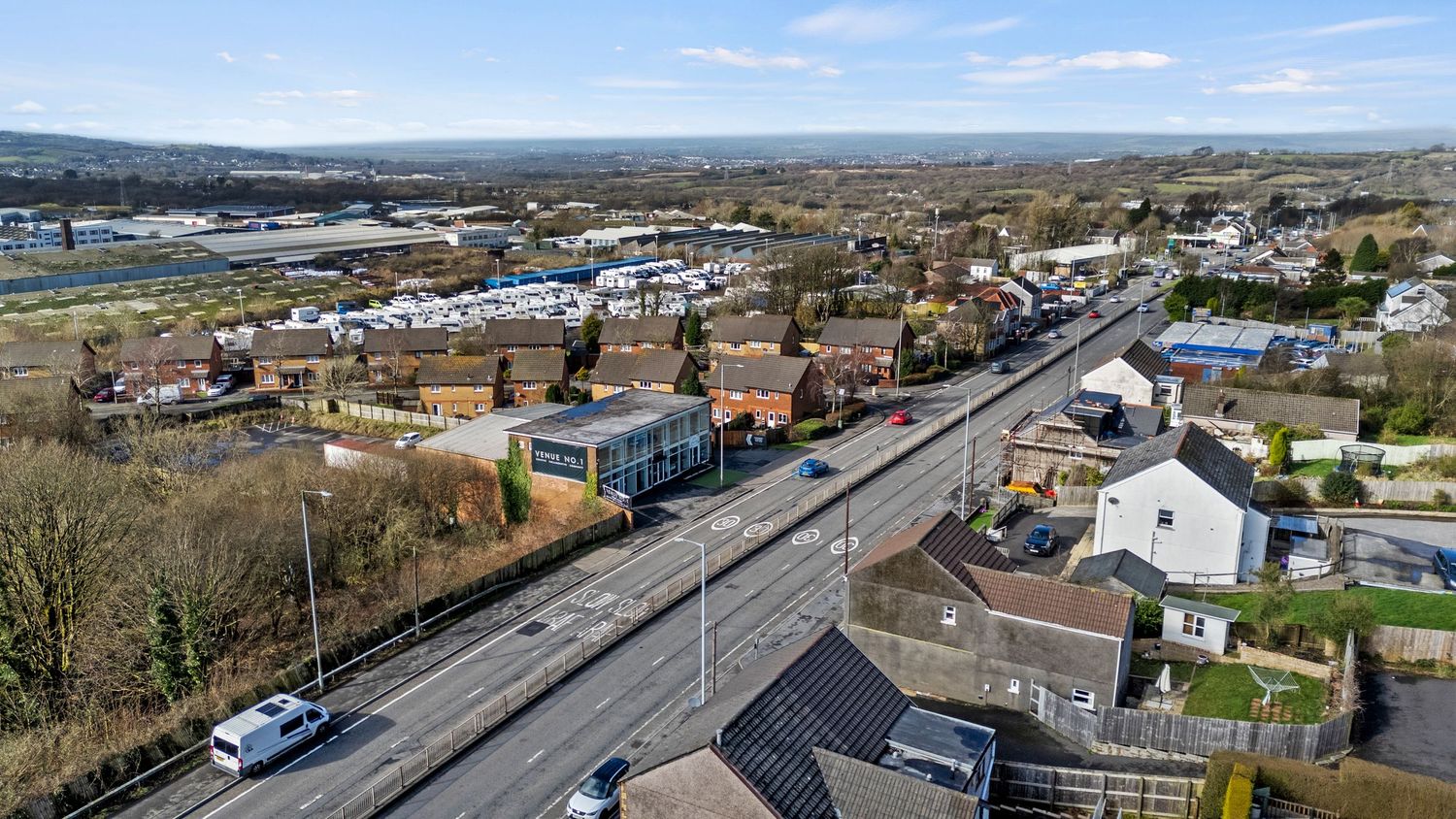 Aerial view of coastal road and residential area with blue skies.