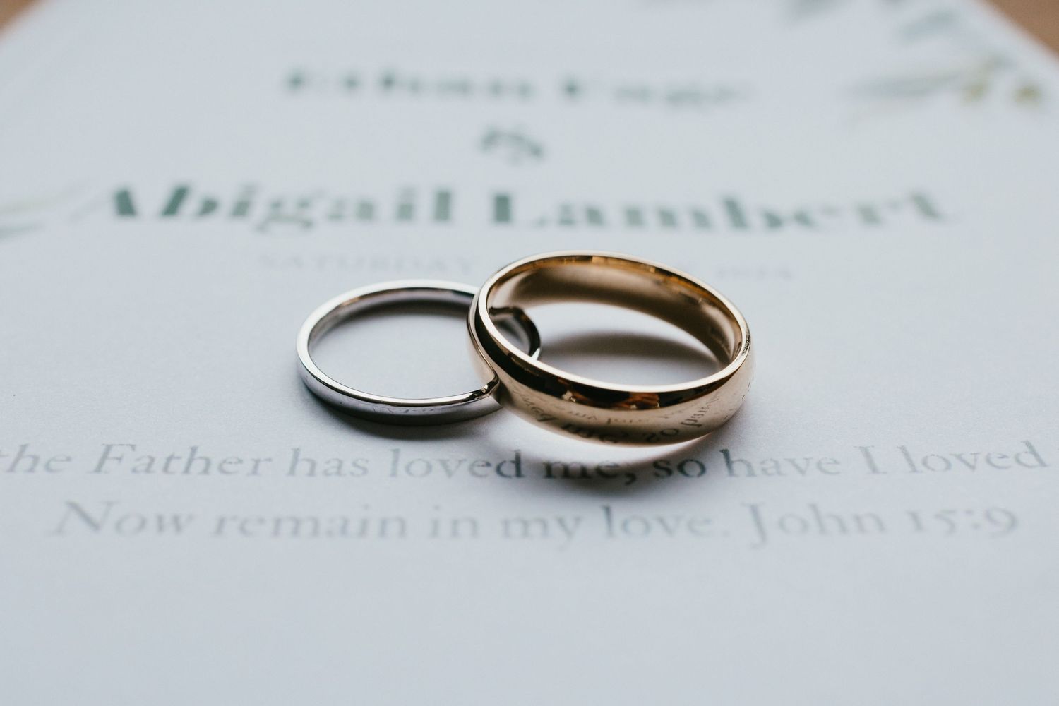 Two wedding rings, one silver and one gold, photographed on printed text.