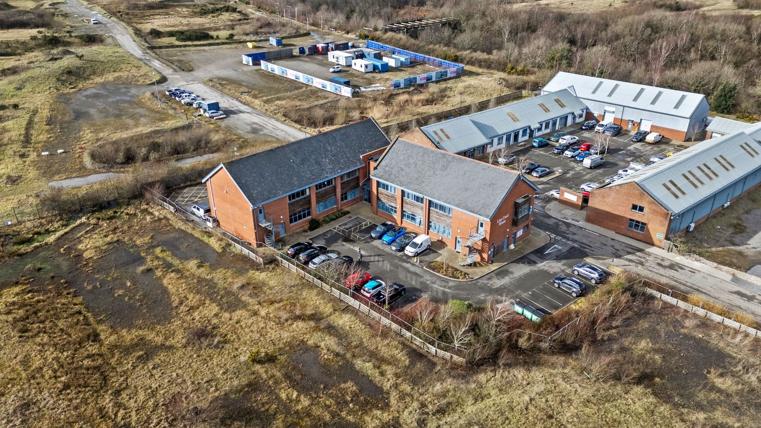 Aerial photograph of brick commercial buildings with parking lots in a rural setting.