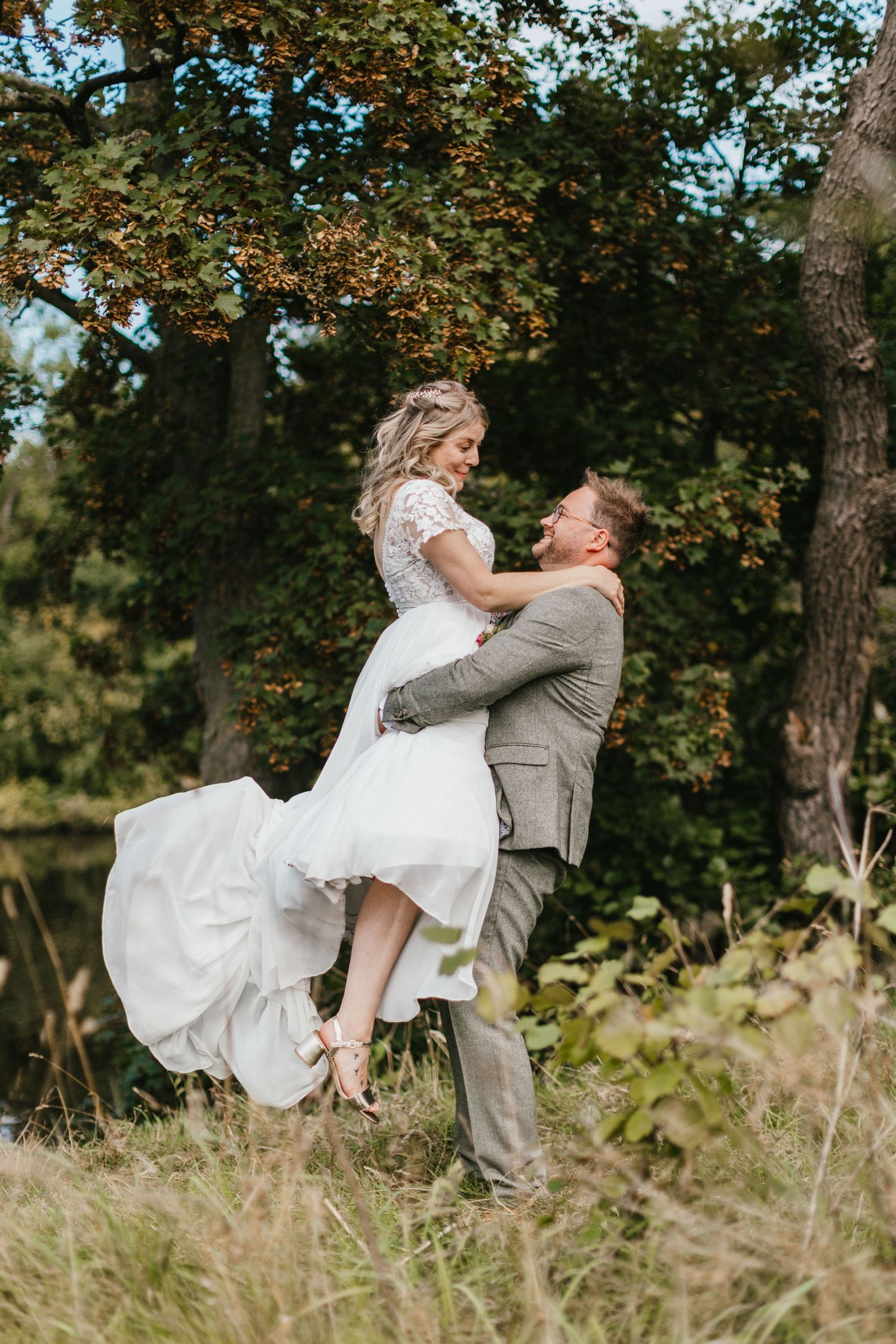 Joyful wedding moment captured outdoors with couple in gray suit and white dress.