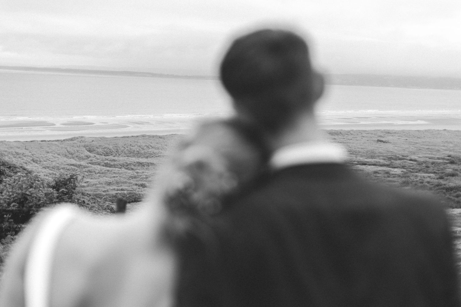 Black and white silhouette of couple overlooking misty valley landscape.