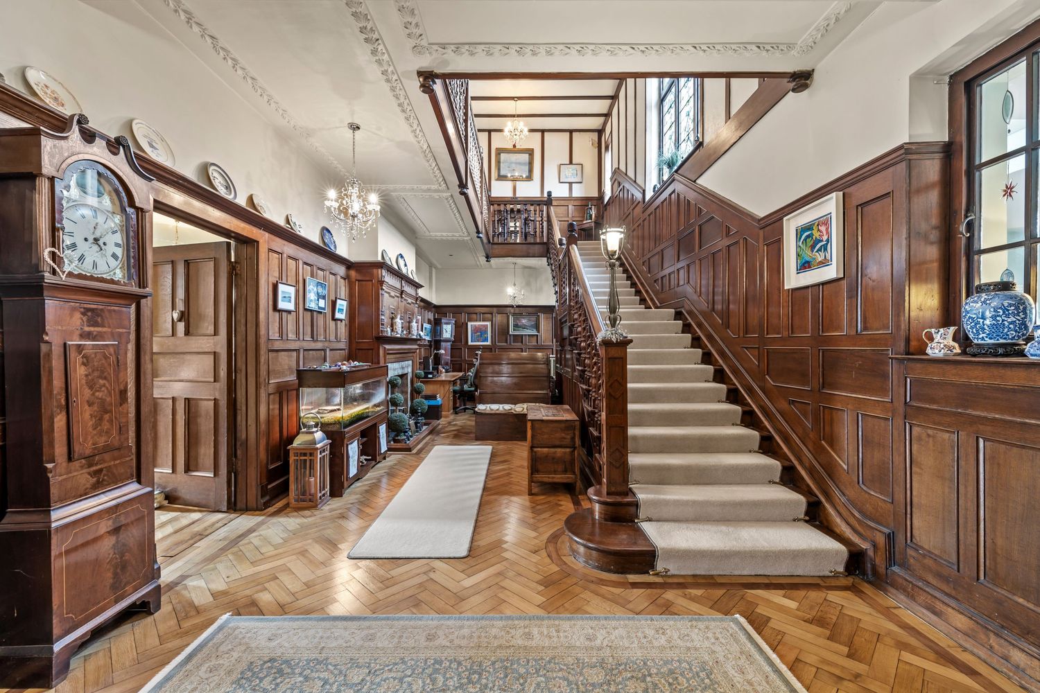 Grand wooden staircase with ornate details in Victorian-style entrance hall.