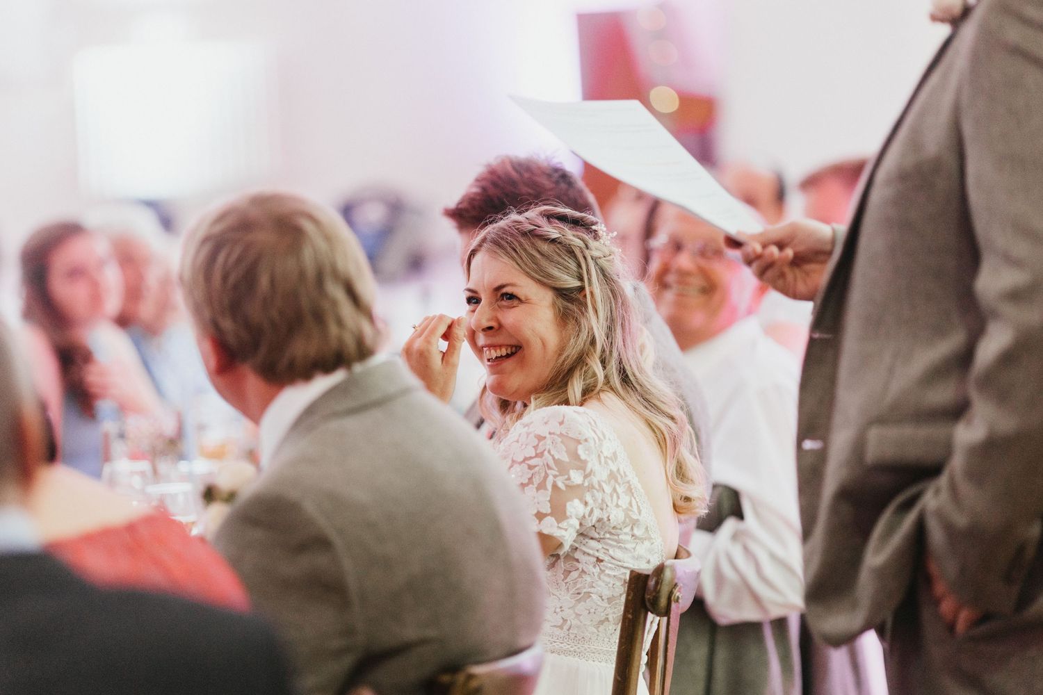 Wedding reception scene with guests laughing and celebrating at decorated tables.