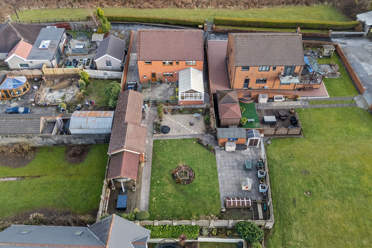 Aerial view of residential properties with brown tiled roofs and enclosed gardens.