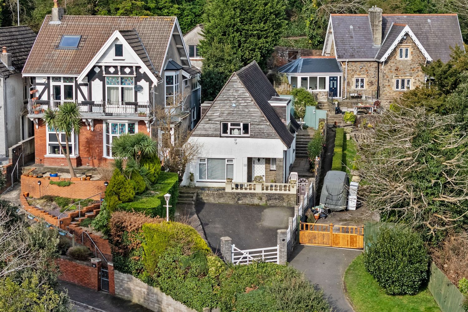 Elevated view of charming Tudor-style houses with driveways and well-maintained gardens.