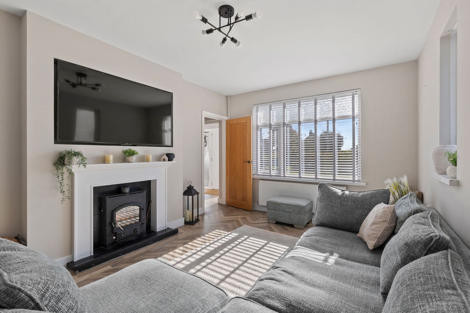 Contemporary living room with mounted TV above fireplace, grey sectional sofa, and city view windows.