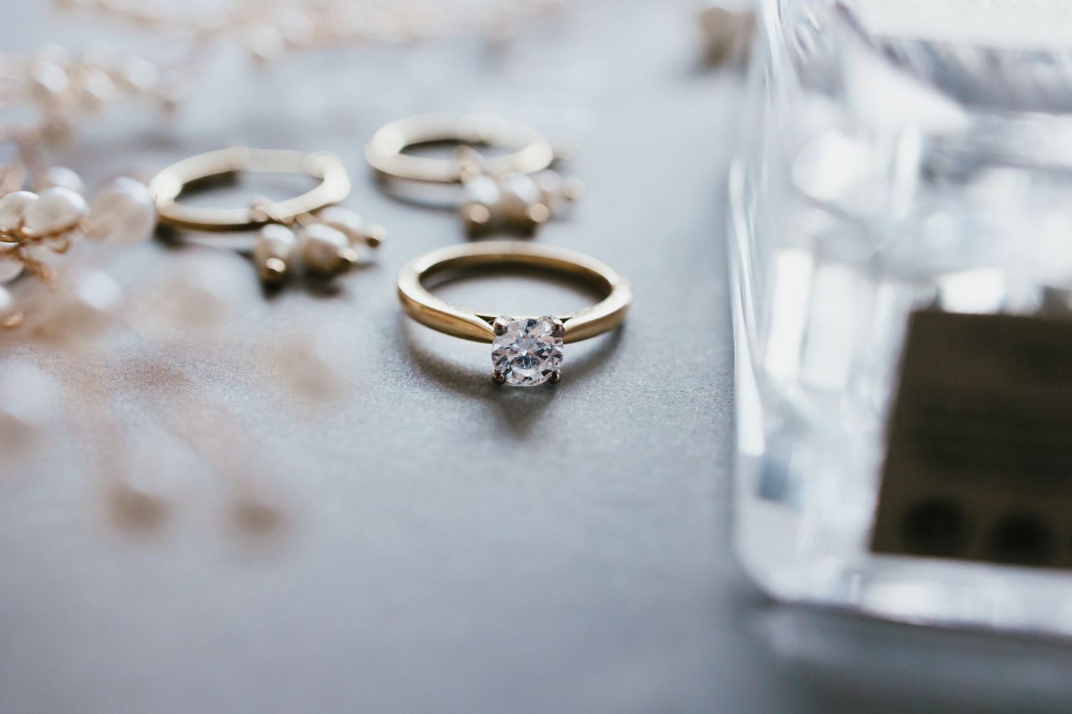 Elegant diamond engagement ring and wedding bands arranged on a light surface.