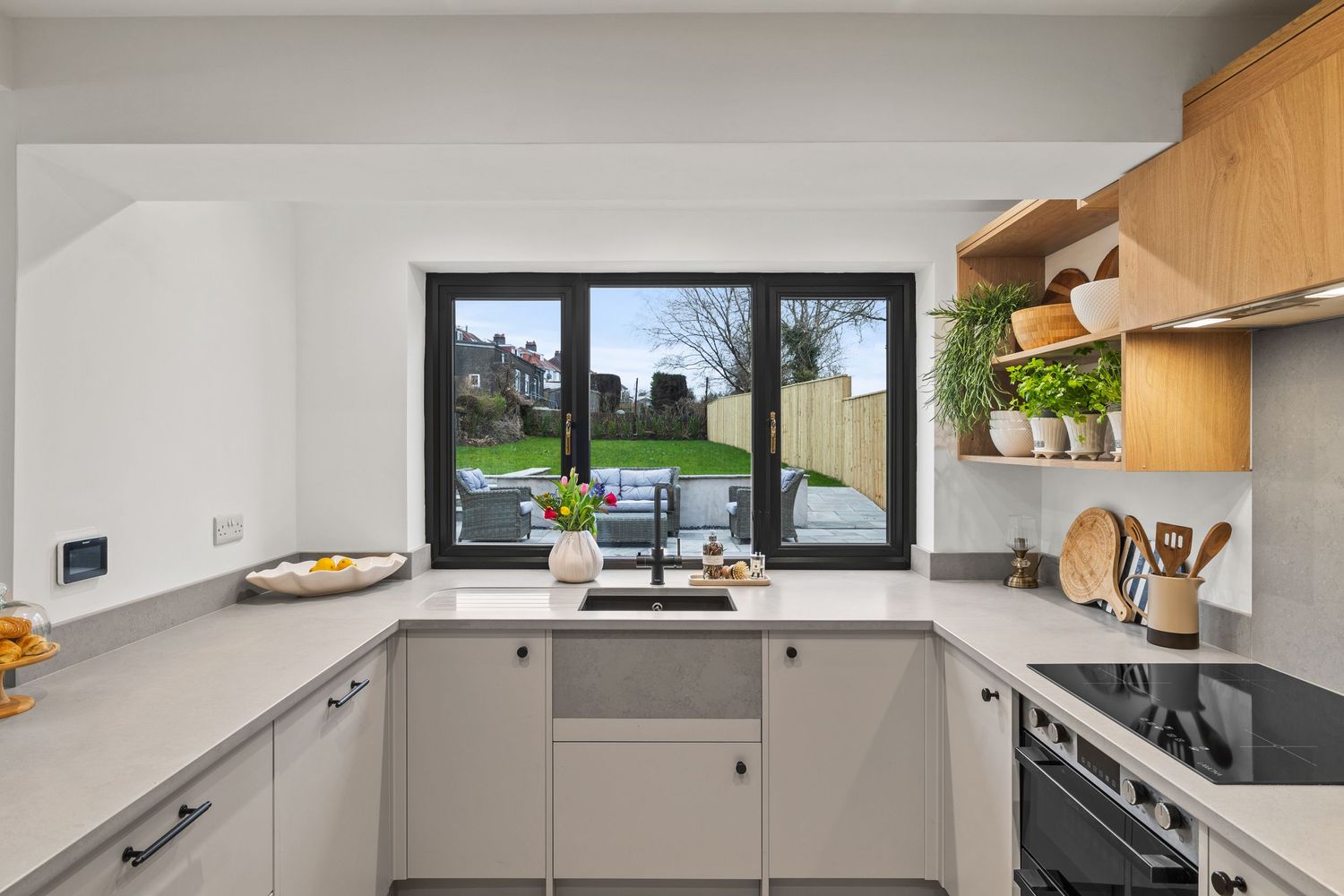 U-shaped kitchen with gray cabinets, black countertops, and a garden view window.