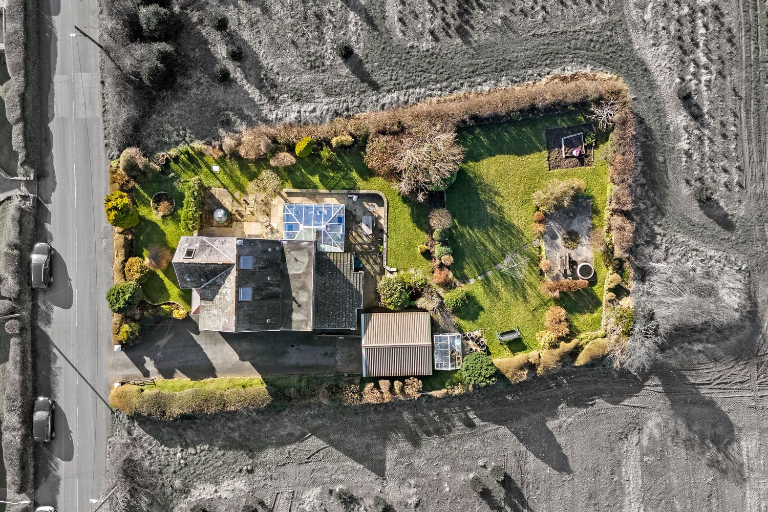 Bird's eye view of a luxury property with swimming pool and landscaped gardens in black and white contrast.