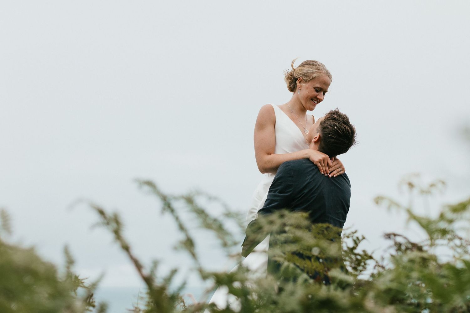 An intimate wedding portrait showing a tender moment between newlyweds against a misty background.