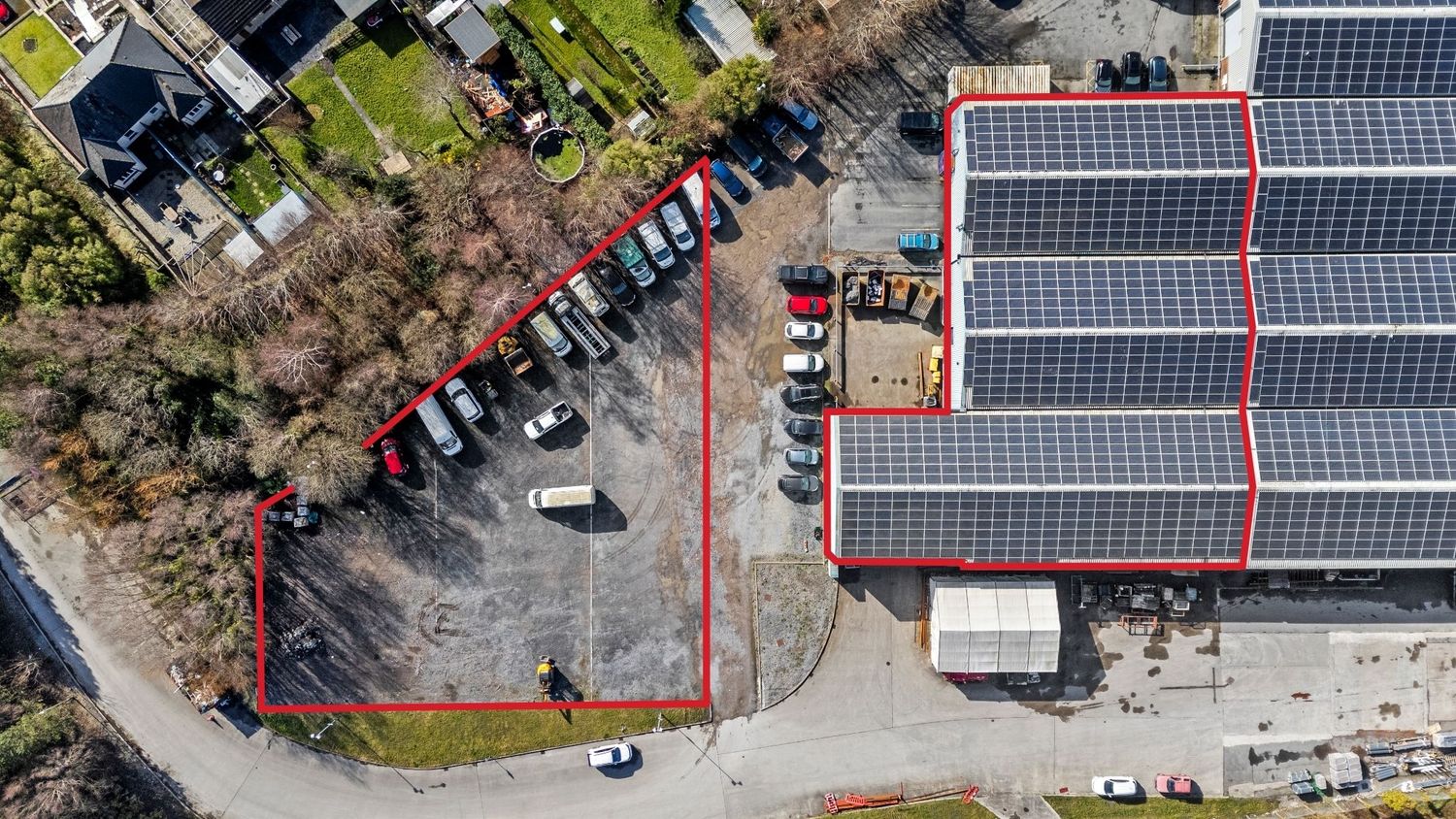 Birds-eye view of a parking area next to a building with solar panels on the roof.