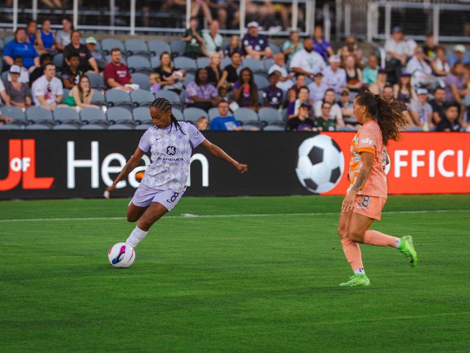 Soccer player slides across grass field during intense match play at professional stadium.