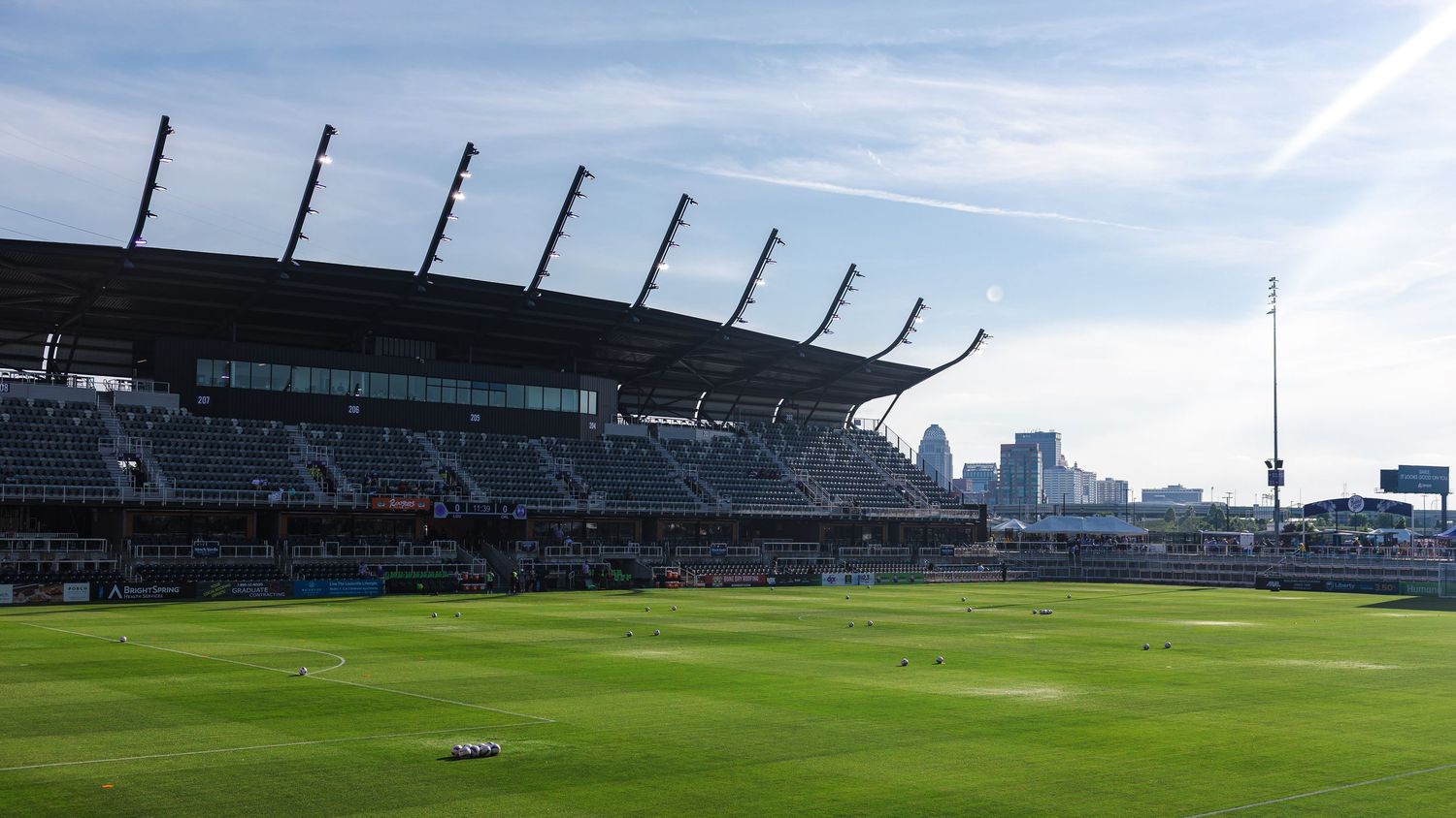 Panoramic view of a professional sports stadium with empty green field and stands under bright daylight.
