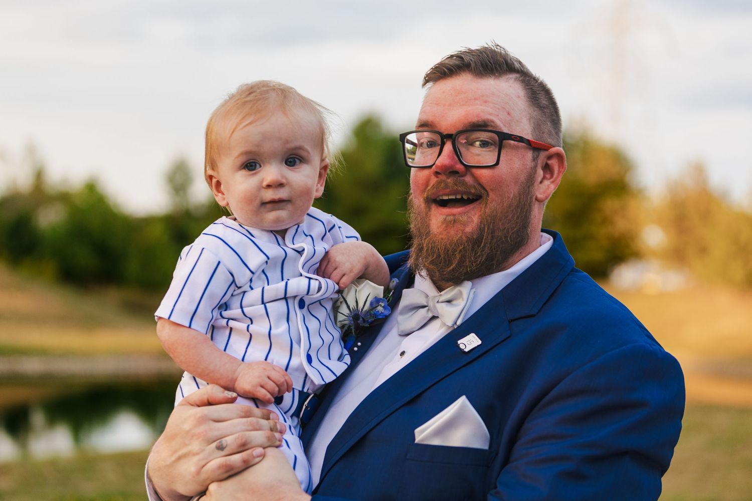 A heartwarming family moment with a small child and adults in formal attire outdoors at sunset.