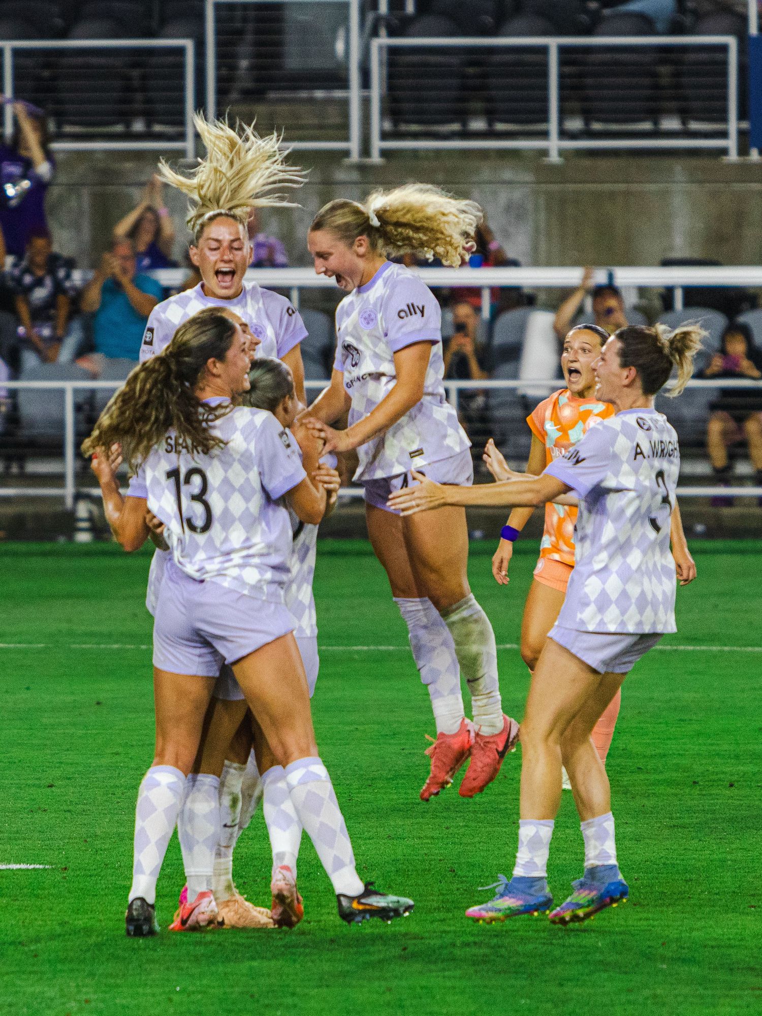 Soccer players celebrating on a grass field with joyful jumping and hugging motions.