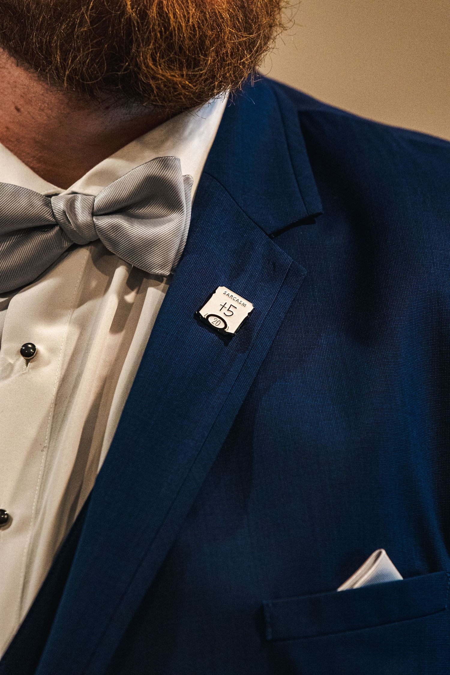 Close-up details of a navy blue suit jacket with white dress shirt and black bow tie for formal attire.