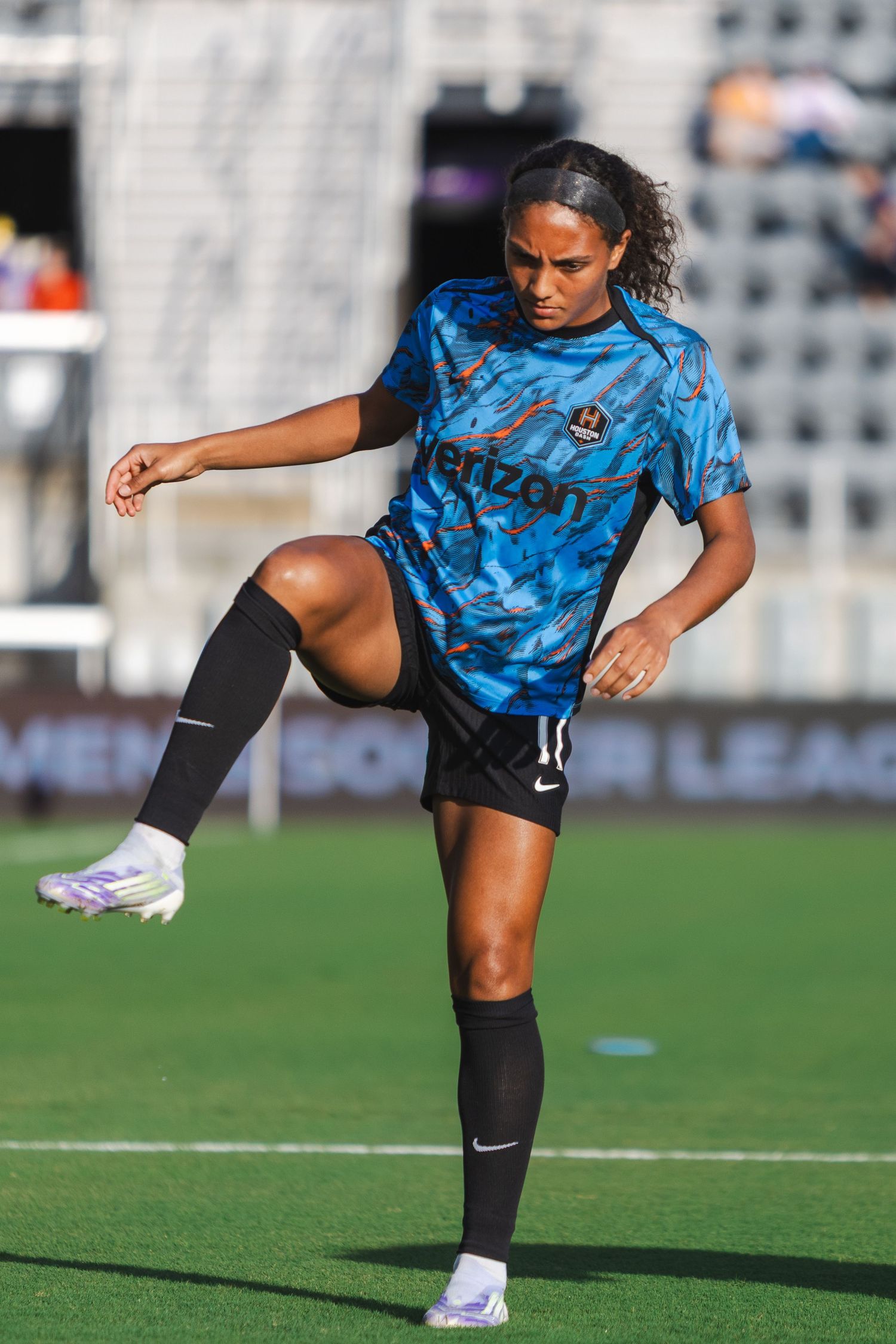 Soccer player in blue camouflage jersey practices kicking drills during training session on sunny field.