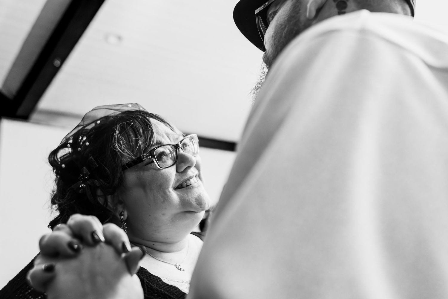 A black and white candid moment captured between two people in conversation, with one wearing glasses.