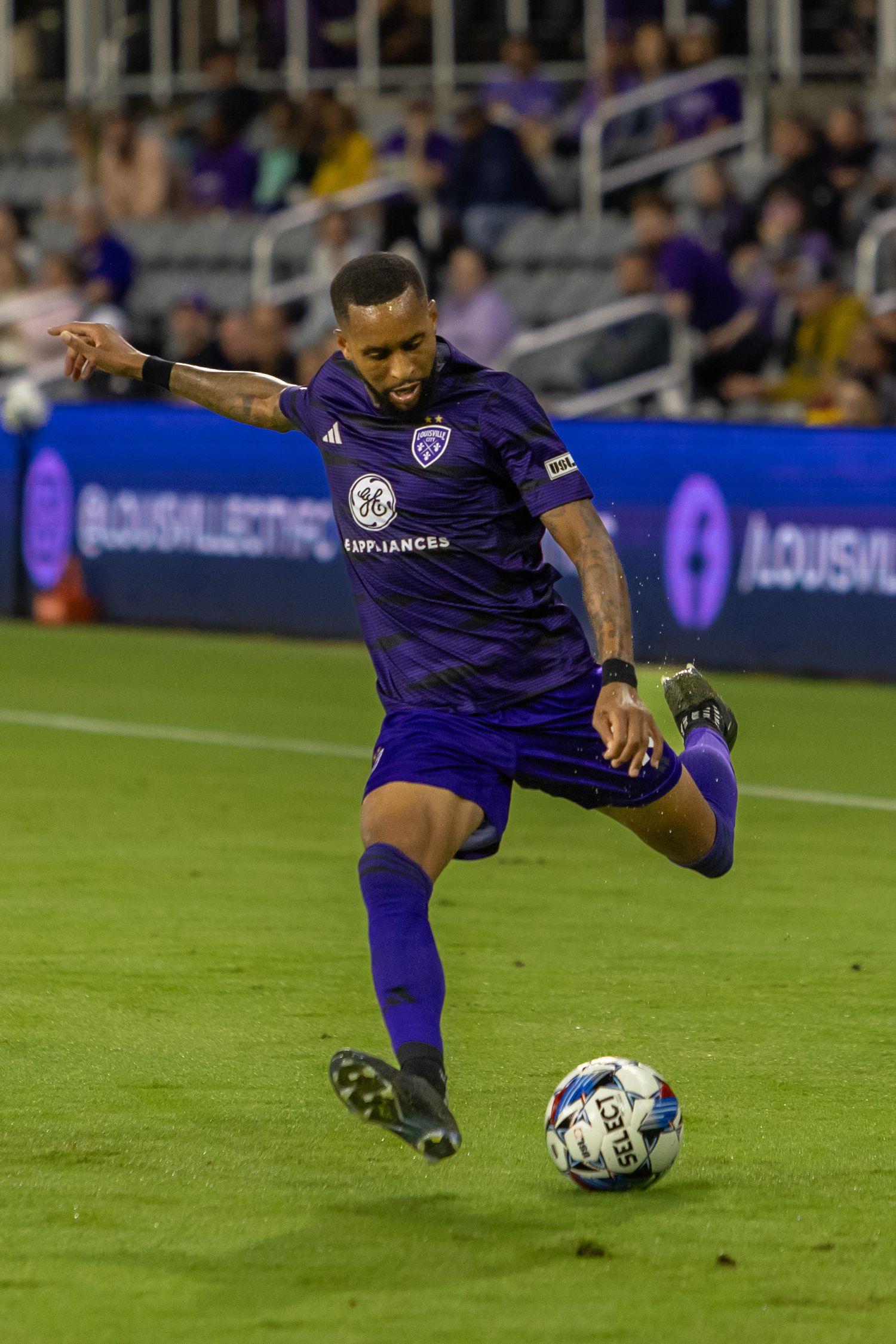 Soccer player in purple uniform performs skillful ball control during match.