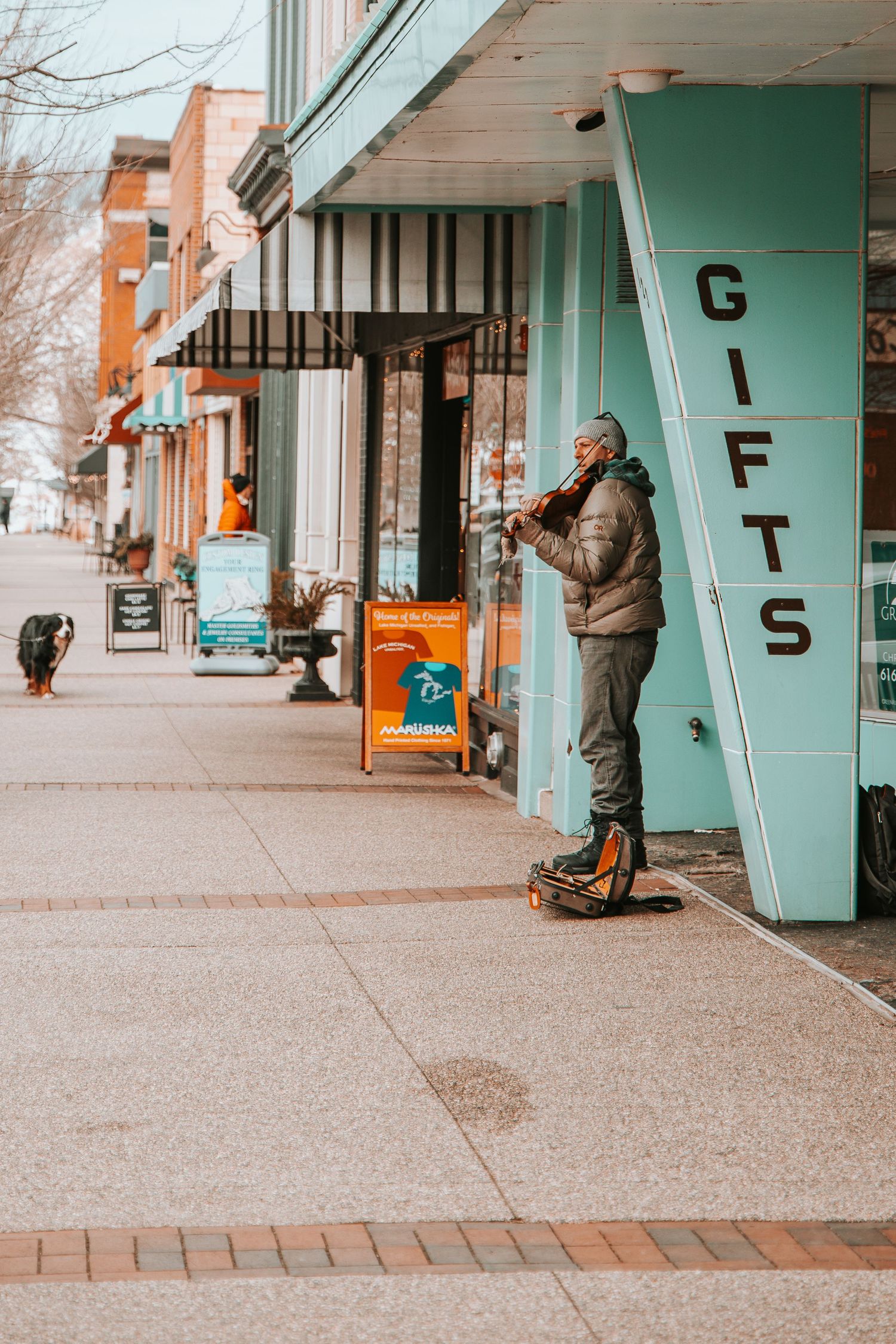 Urban street scene showing storefront with 'GIFTS' sign and person standing outside on sidewalk.