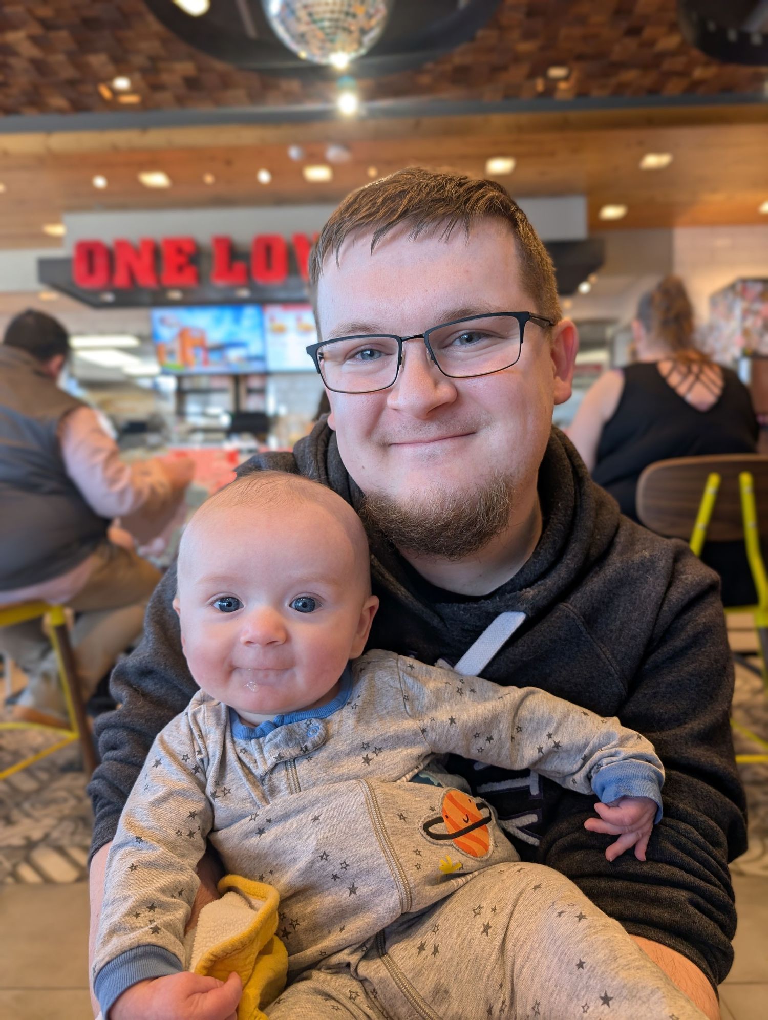 Casual dining scene at a restaurant with adult and baby sitting together at table.
