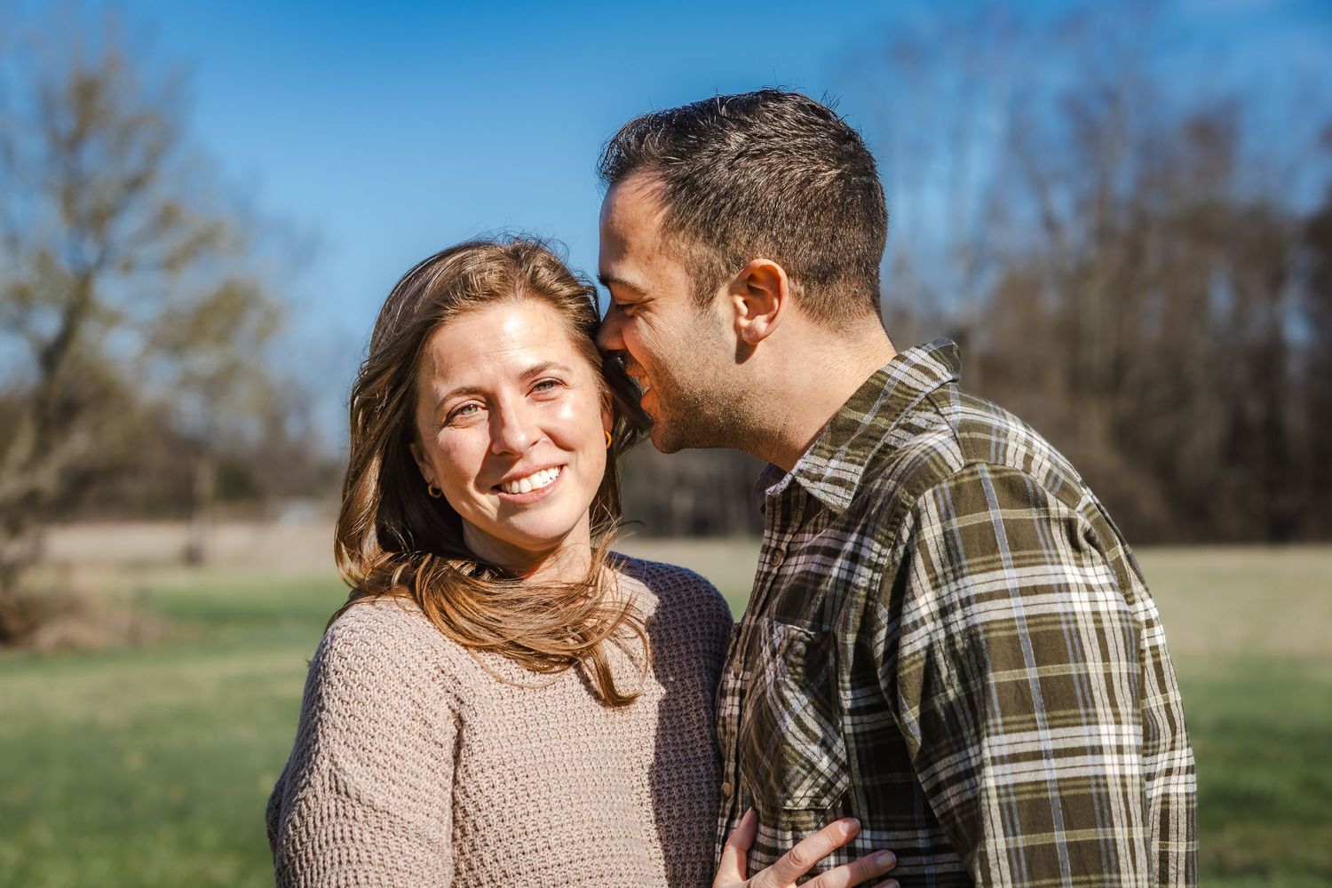 Loving couple sharing a tender moment in a sunny field.