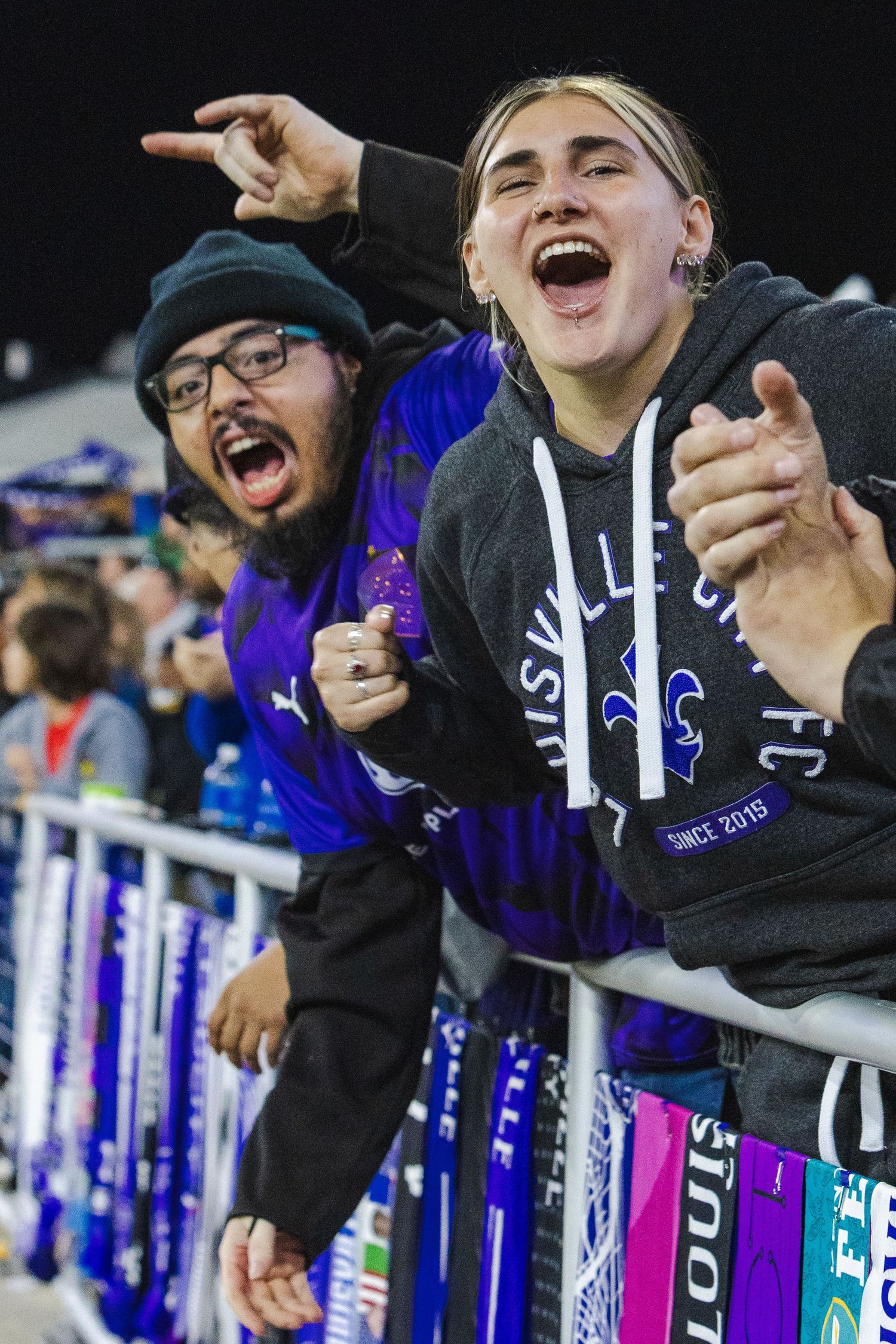 Enthusiastic fans cheer from the stands during a soccer match.