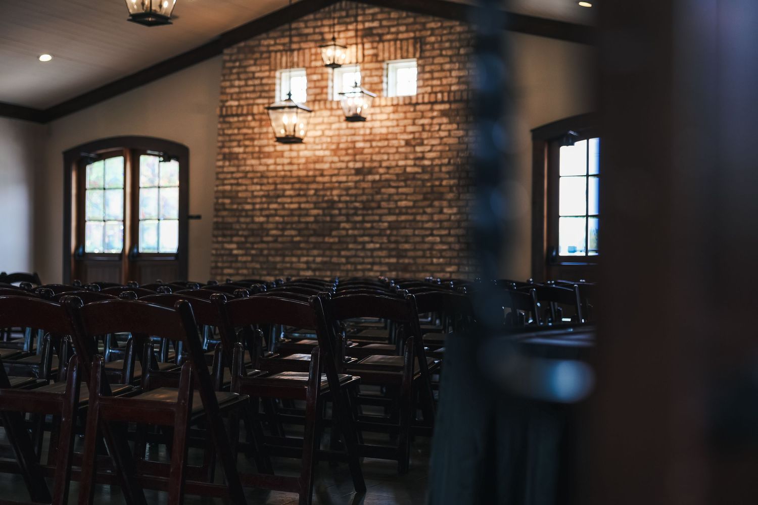 Rustic restaurant interior with exposed brick walls, pendant lighting, and dark wooden furniture creates cozy ambiance.