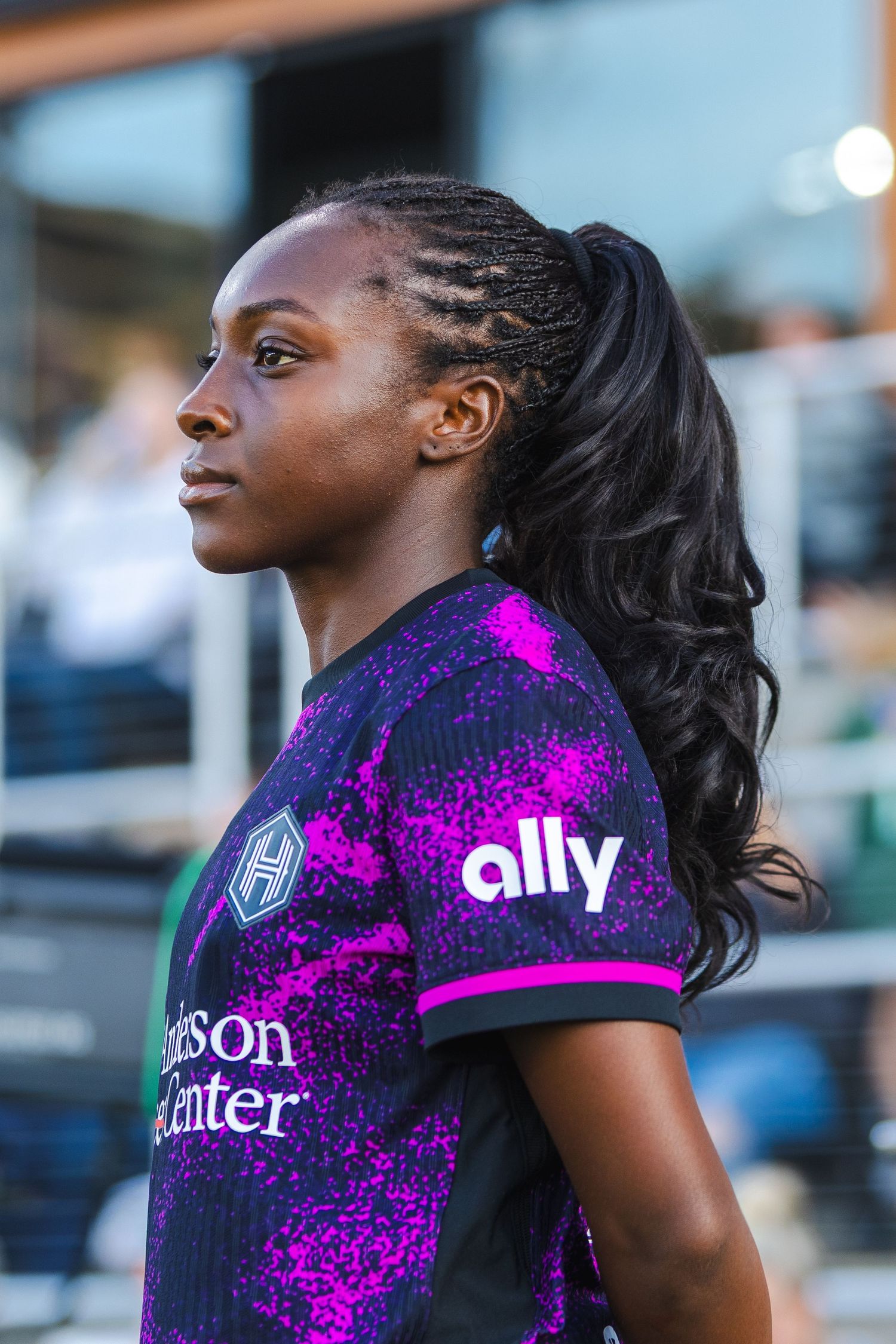 Professional athlete wearing purple and pink splatter pattern jersey with sponsor logos during competition.