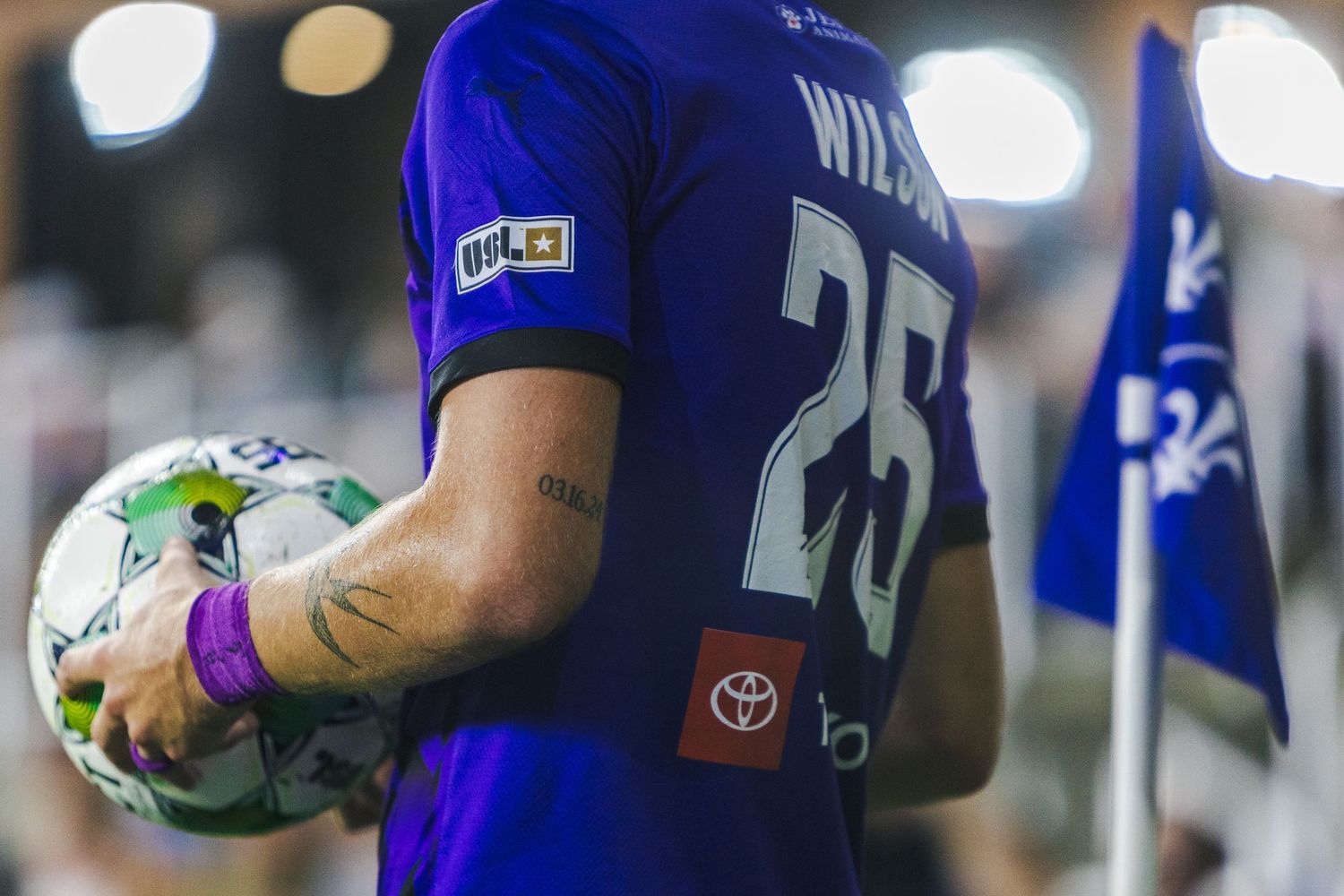 Soccer players in blue jerseys hold water bottles and hydrate during a break in the match.