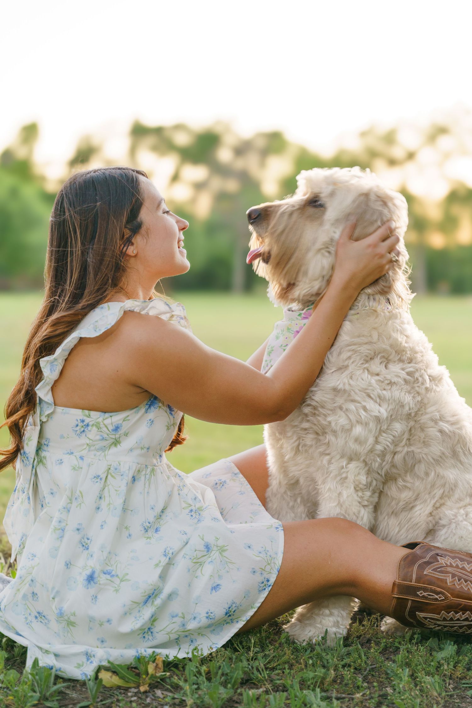 Young girl in floral dress playing with a Golden Doodle dog, in sunny field at Liberty Park located at 500 E Avenue K, Belton, TX 76513