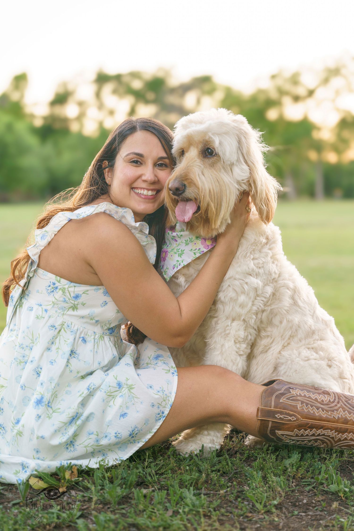 Woman sitting on grass hugging her fluffy dog during an outdoor lifestyle portrait at golden hour.