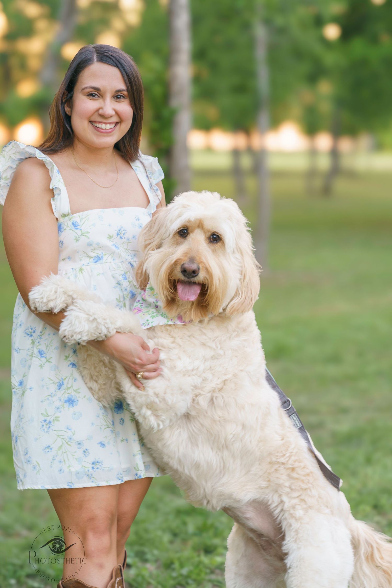 Woman standing outdoors holding her dog upright during a lifestyle portrait session.