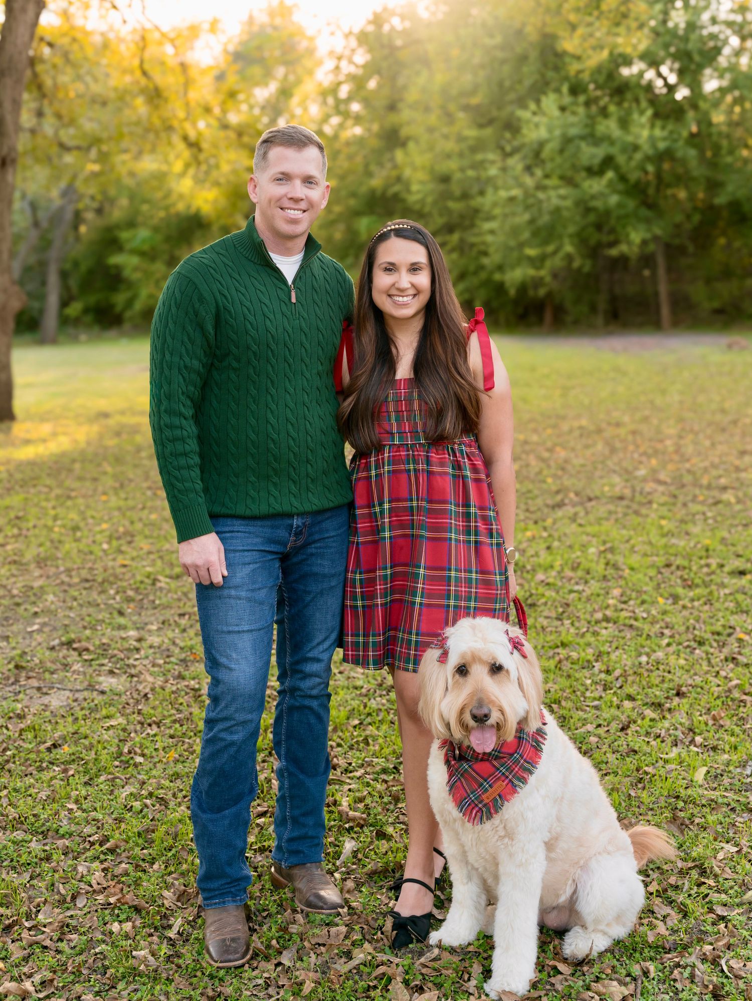 Couple standing outdoors in a park with their dog, posing together during a fall portrait session