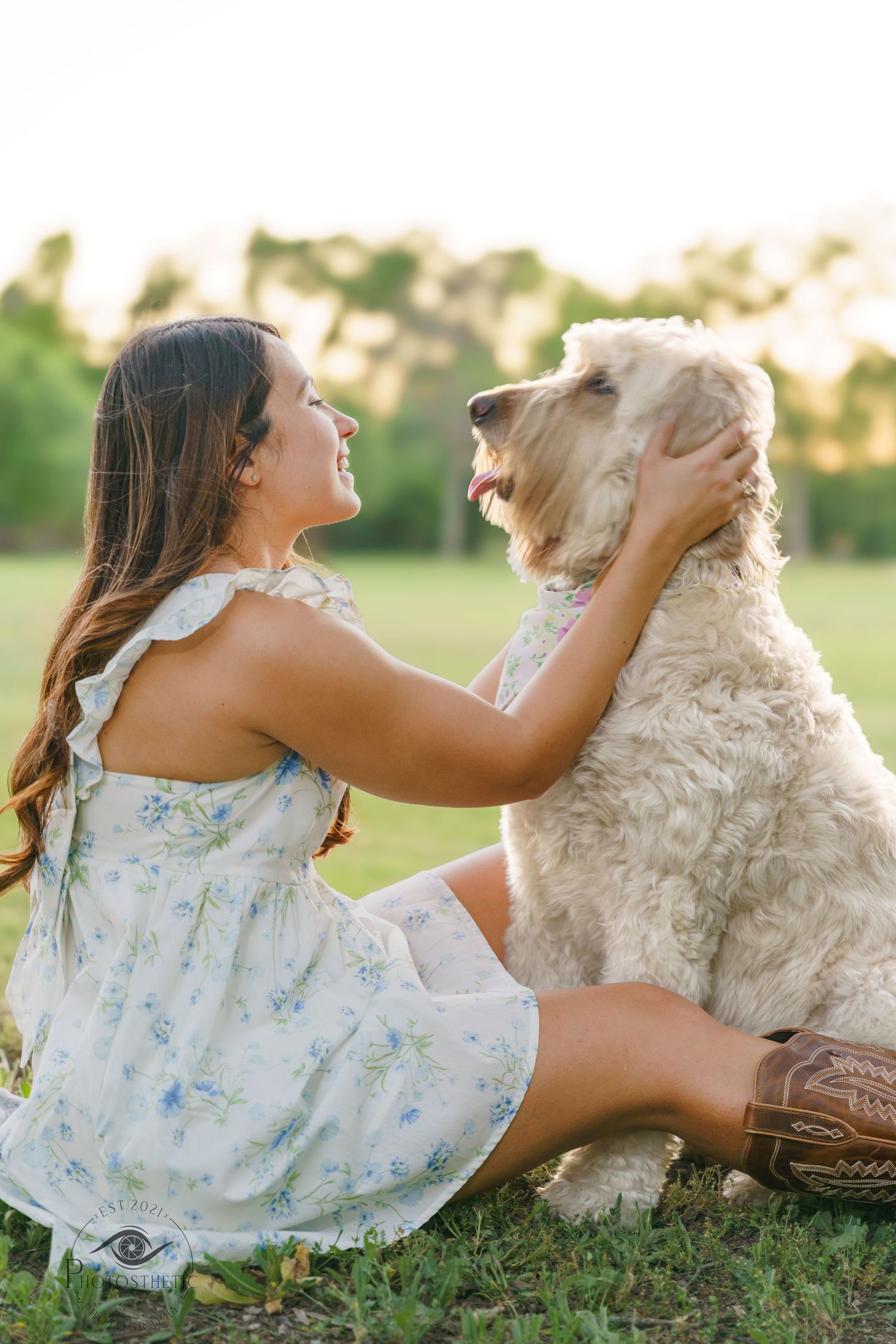 Woman sitting on the grass facing her dog, sharing a quiet moment outdoors in natural light.