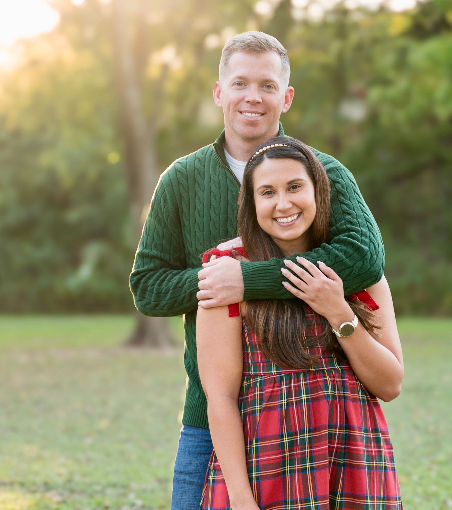 Couple smiling and hugging outdoors during a fall portrait session in a park.