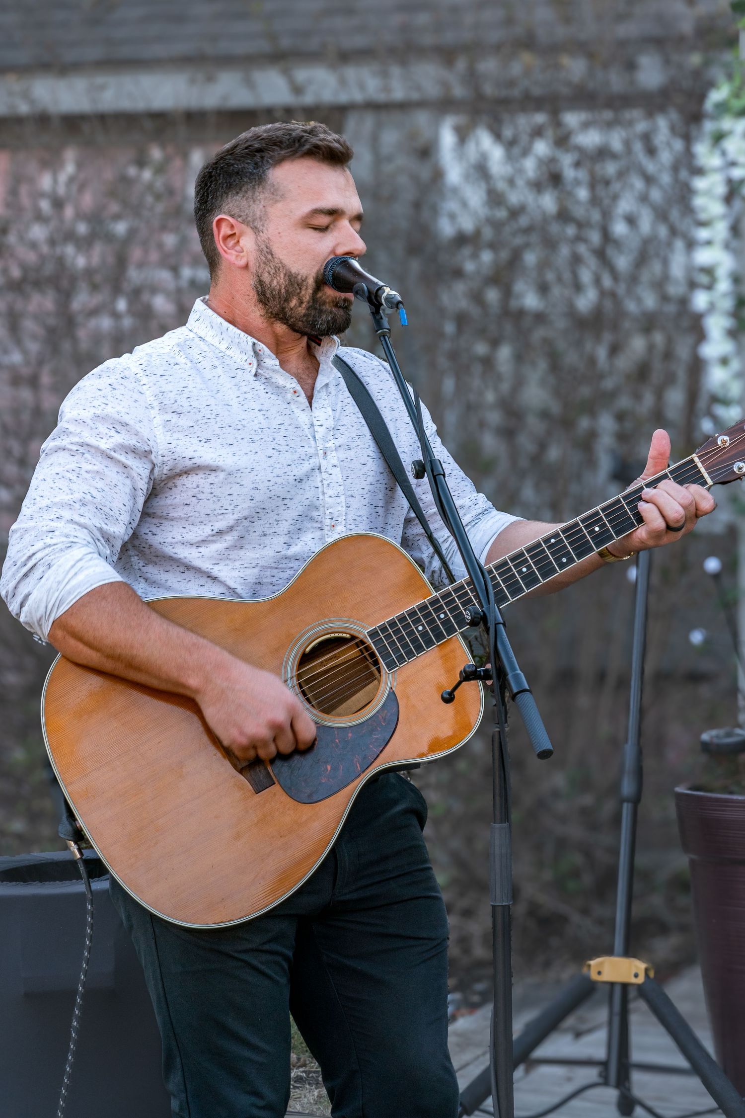 A musician in a white shirt plays an acoustic guitar on stage in a series of progressive performance shots.