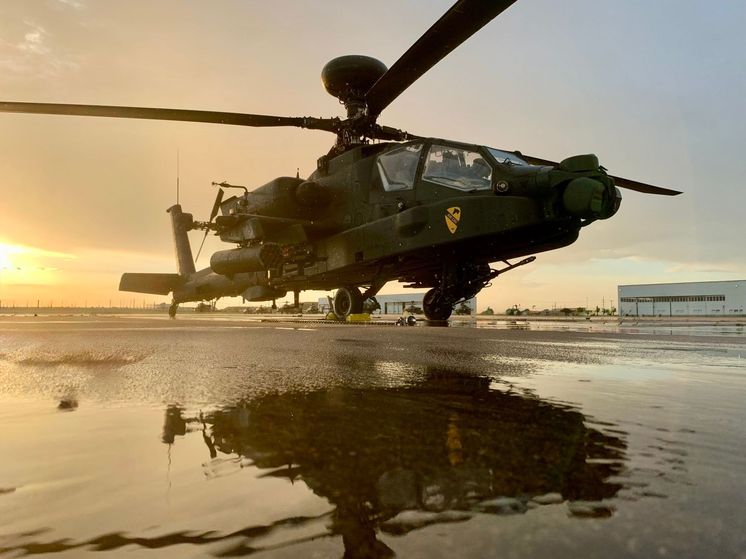 Military aircraft silhouettes against sunset on a beach with reflections in the water.