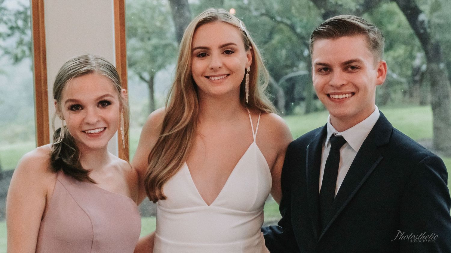 Bride posing with two family members during a wedding portrait indoors.