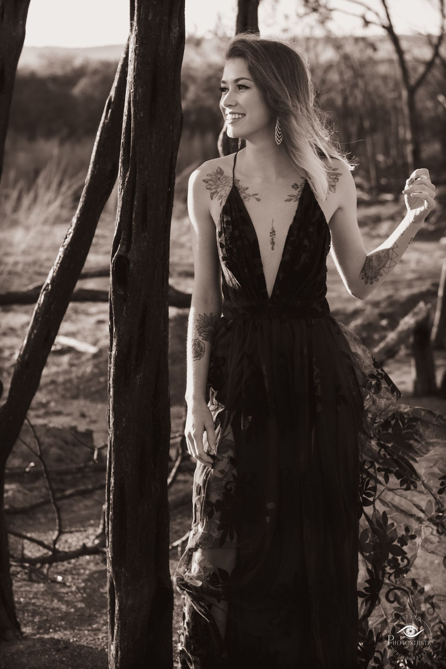 Color washed photograph of a woman in dress poses in wooded area with dramatic lighting near Belton Lake.