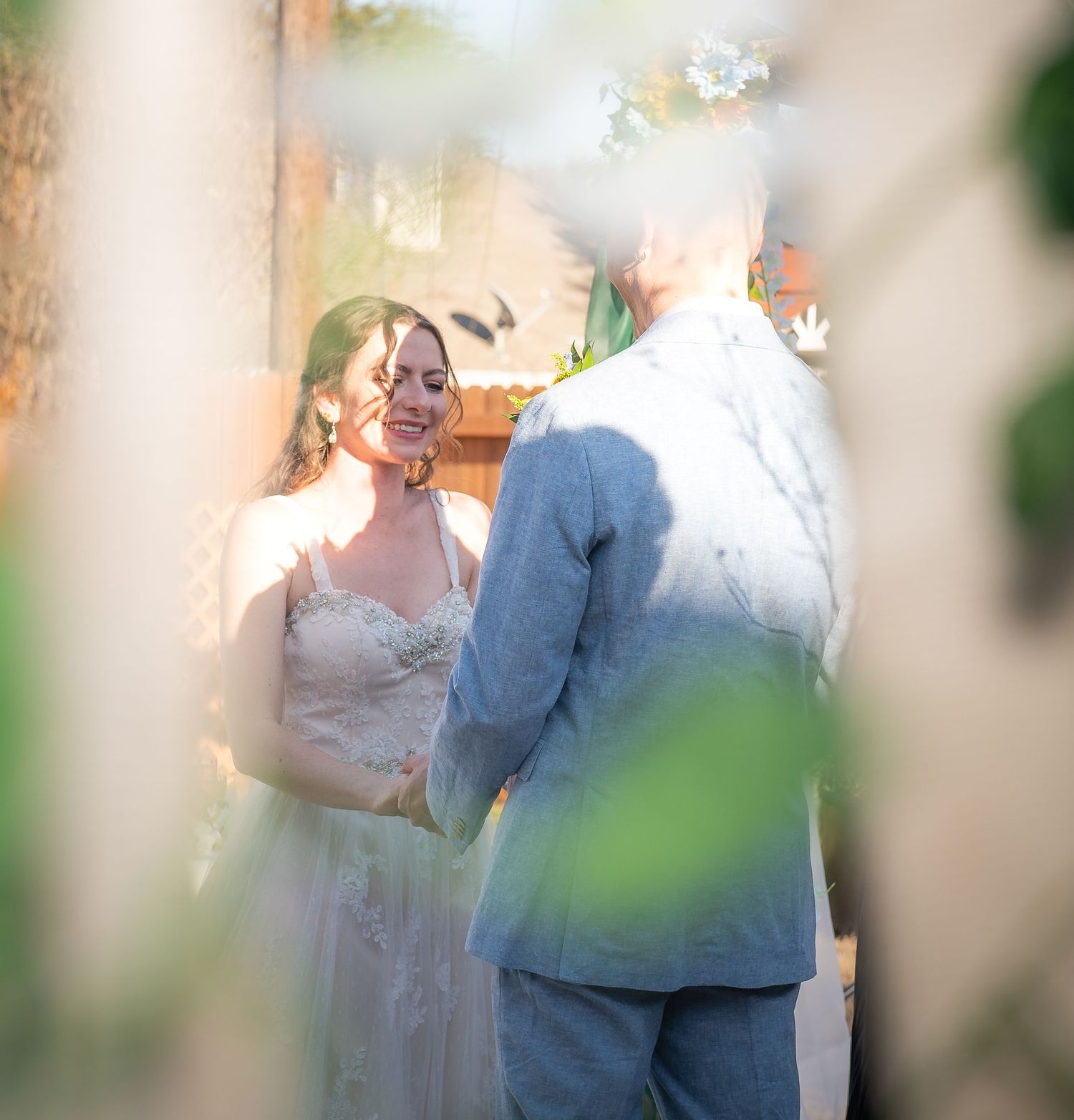 A romantic wedding moment captured through foliage with soft natural lighting and dreamy bokeh effects located in beautiful Hewitt, Texas