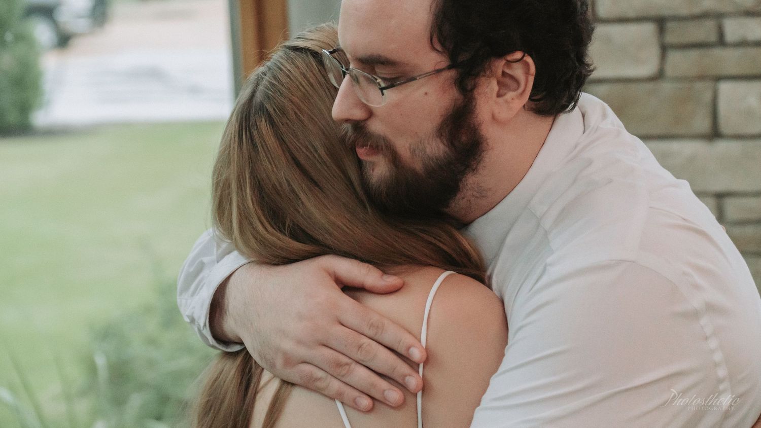 Bride embracing a loved one during an emotional moment at an indoor wedding.
